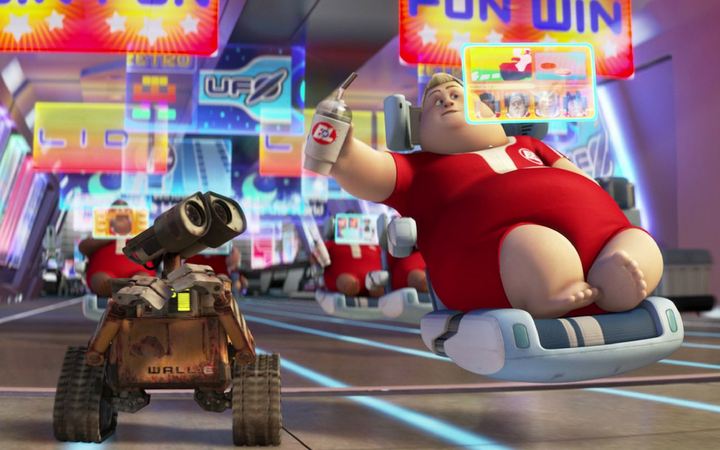 Wall-E the robot rolling next to a human in a floating chair drinking from a cup and watching a projected screen.